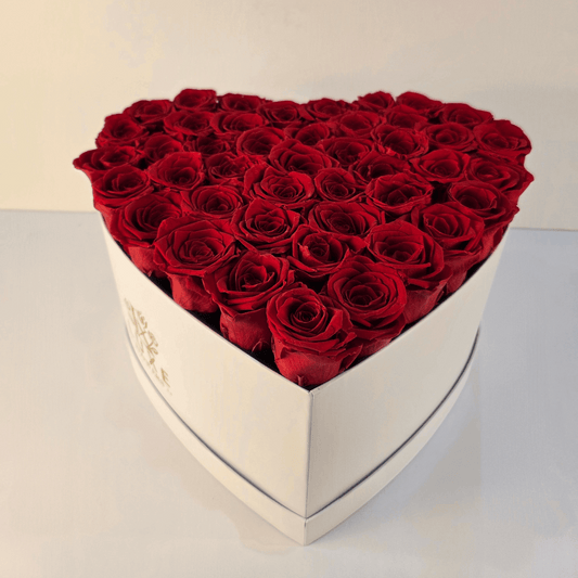 Heart-shaped bouquet of red roses in a white box on a light background